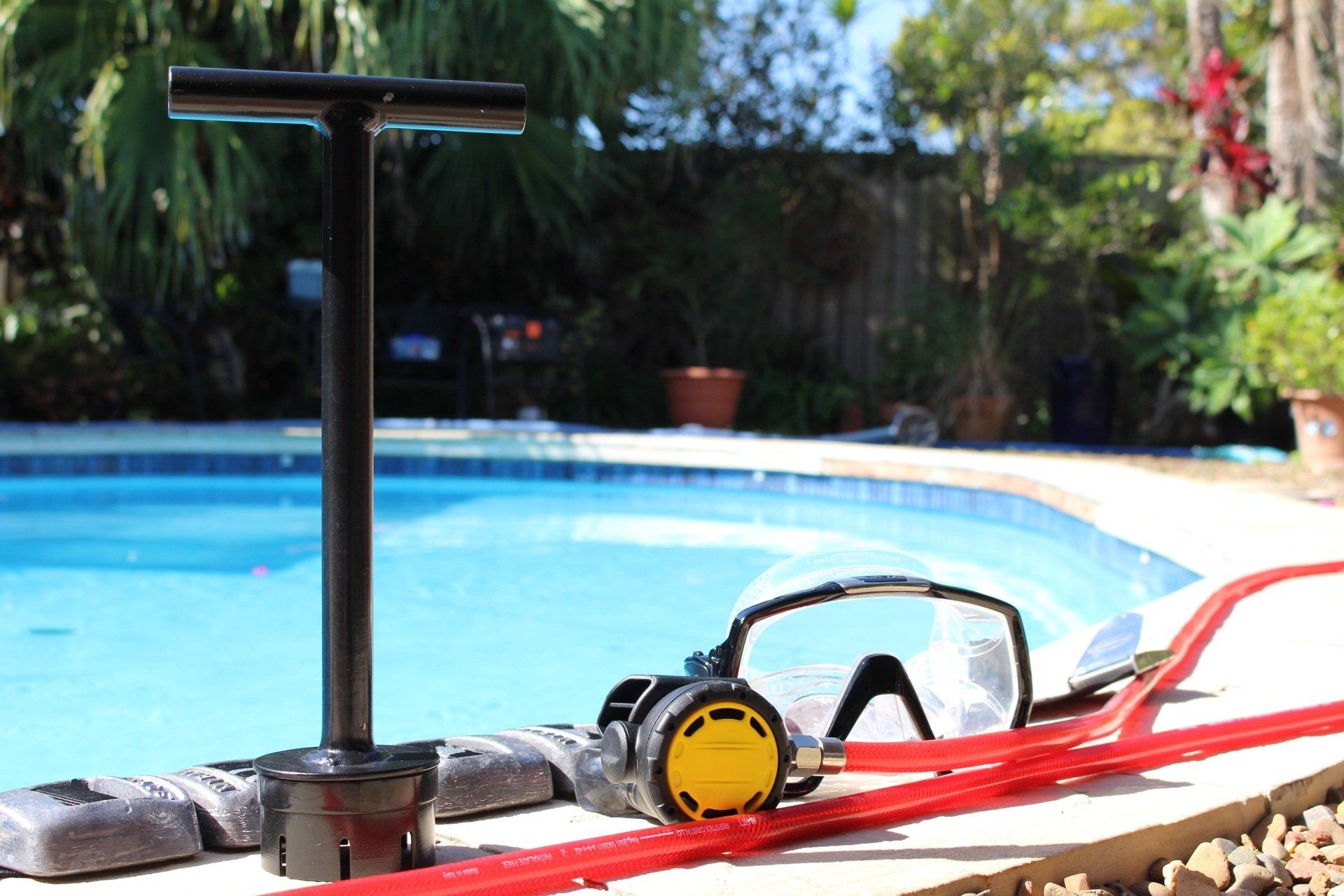 A scuba diving mask and goggles are sitting next to a pool.