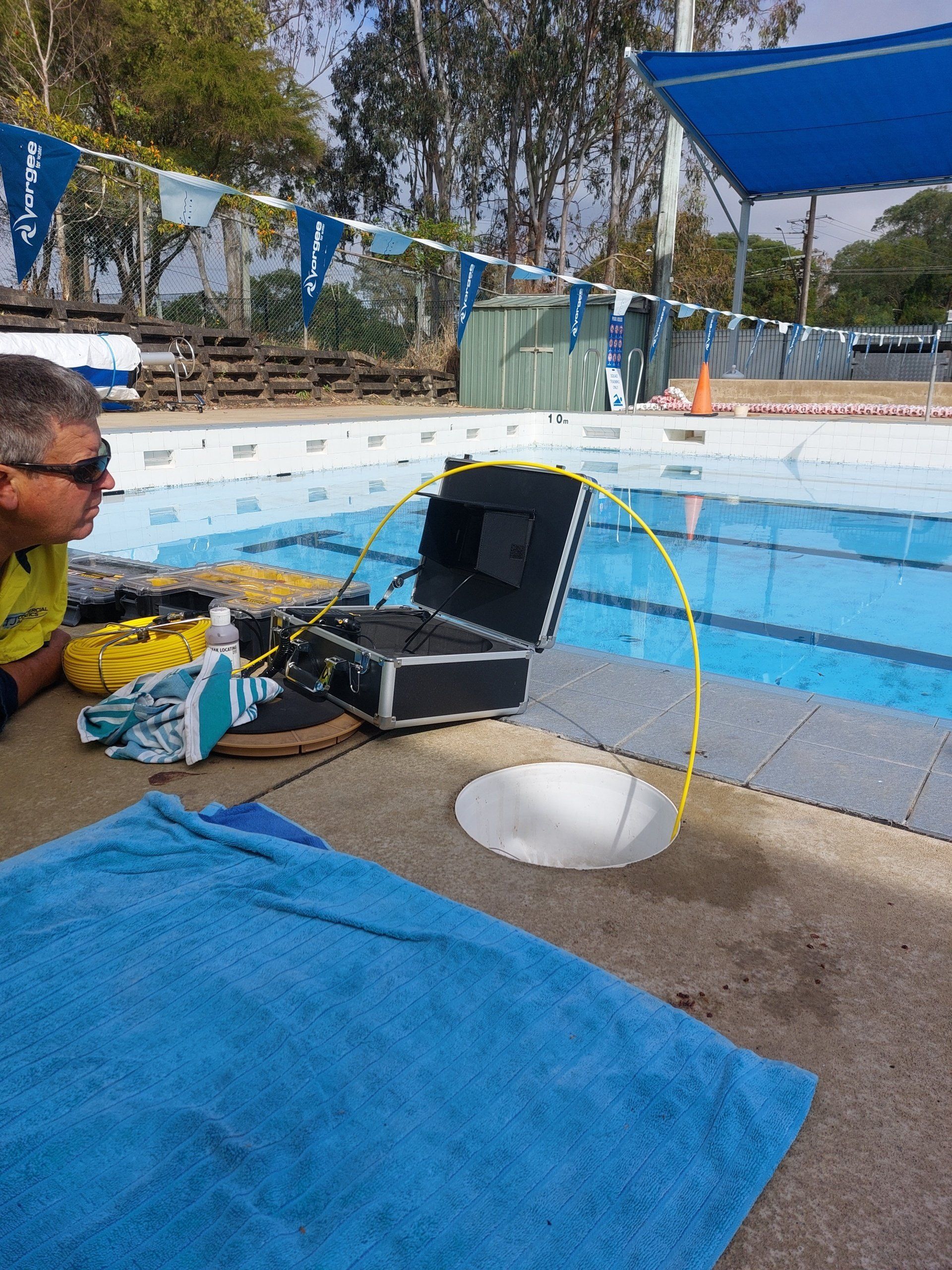 A man is working on a device next to a swimming pool
