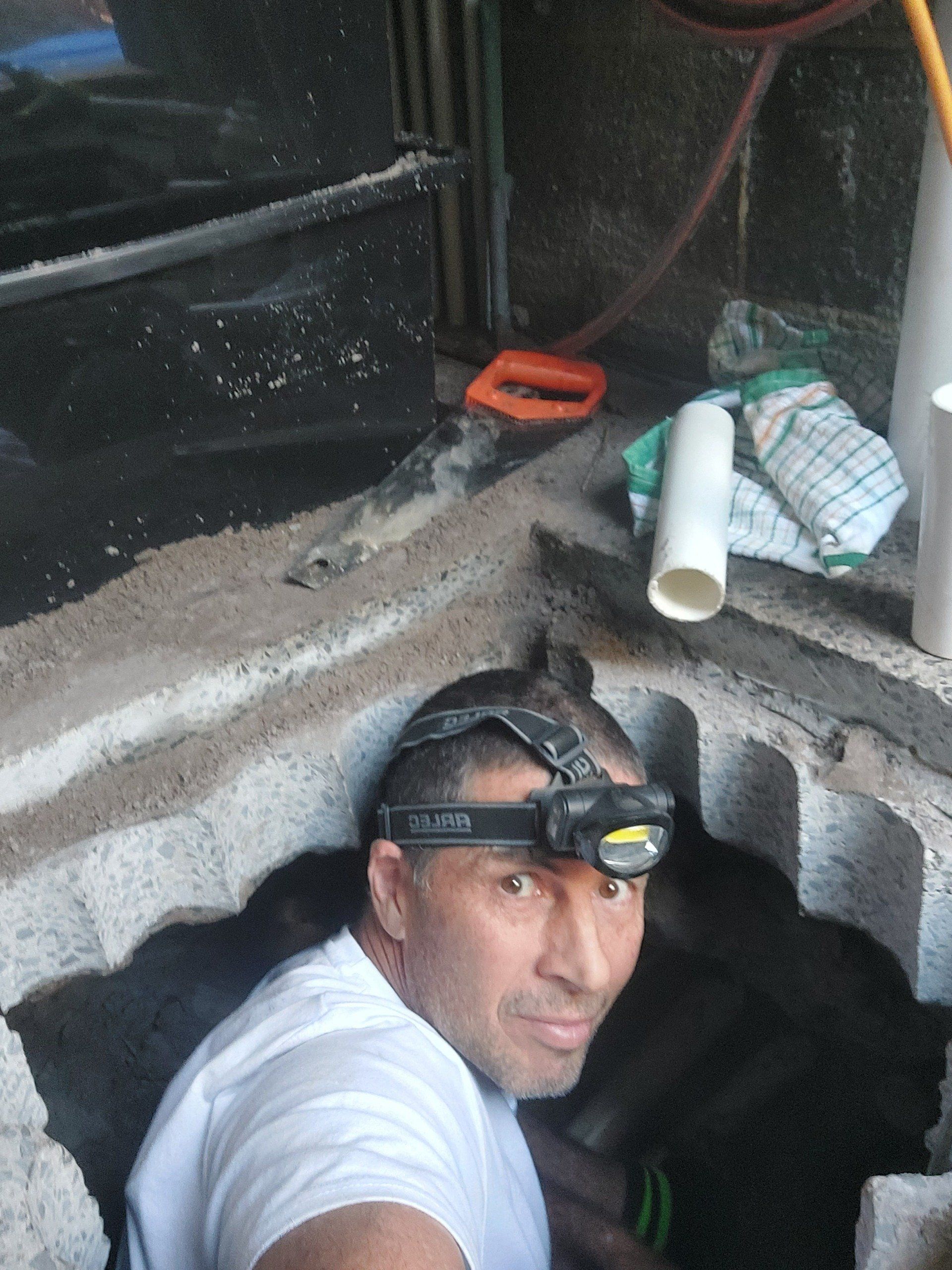 A man wearing a headlamp is standing in a hole