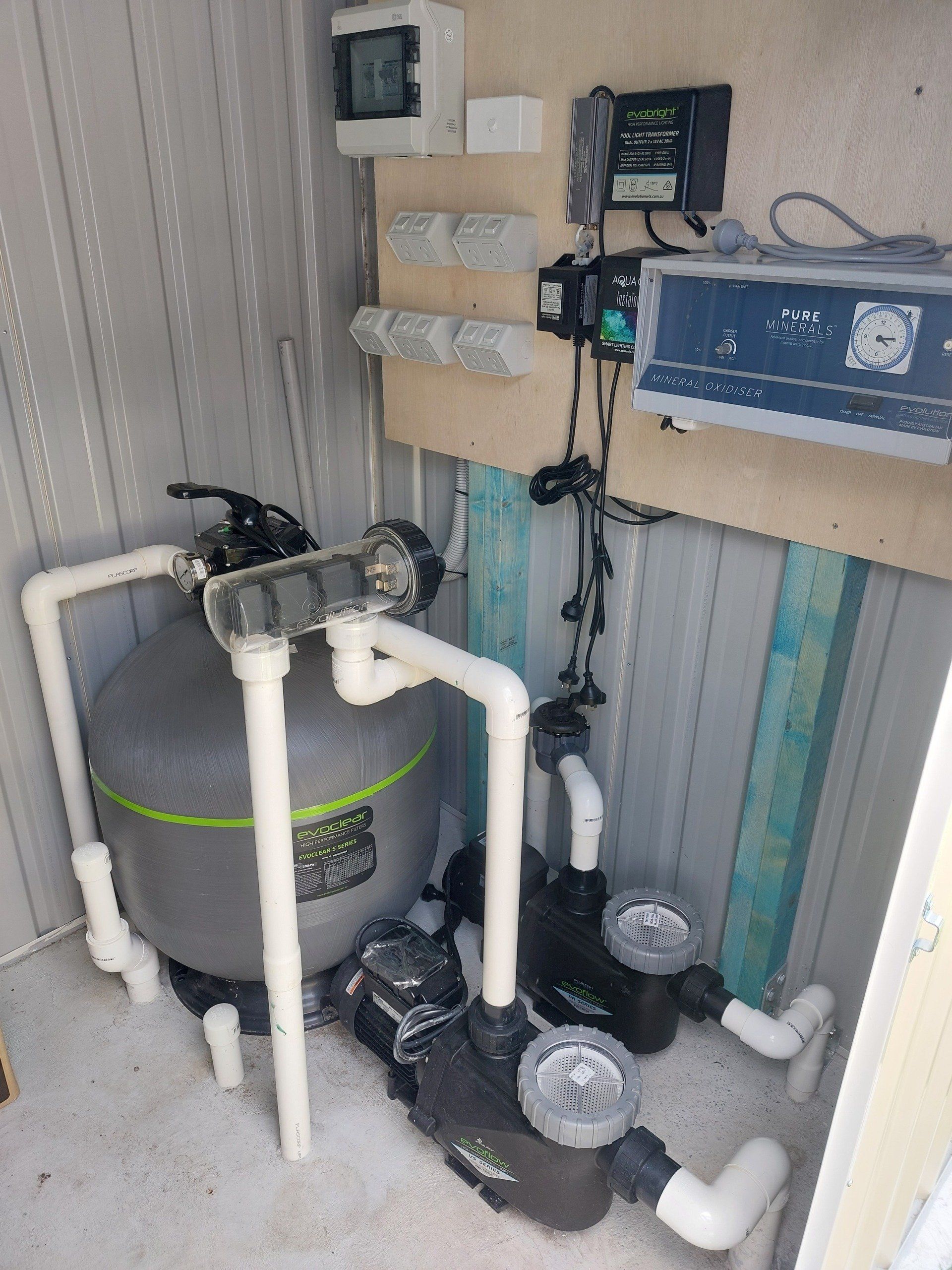 A room with a pool filter , pumps , and a clock on the wall.