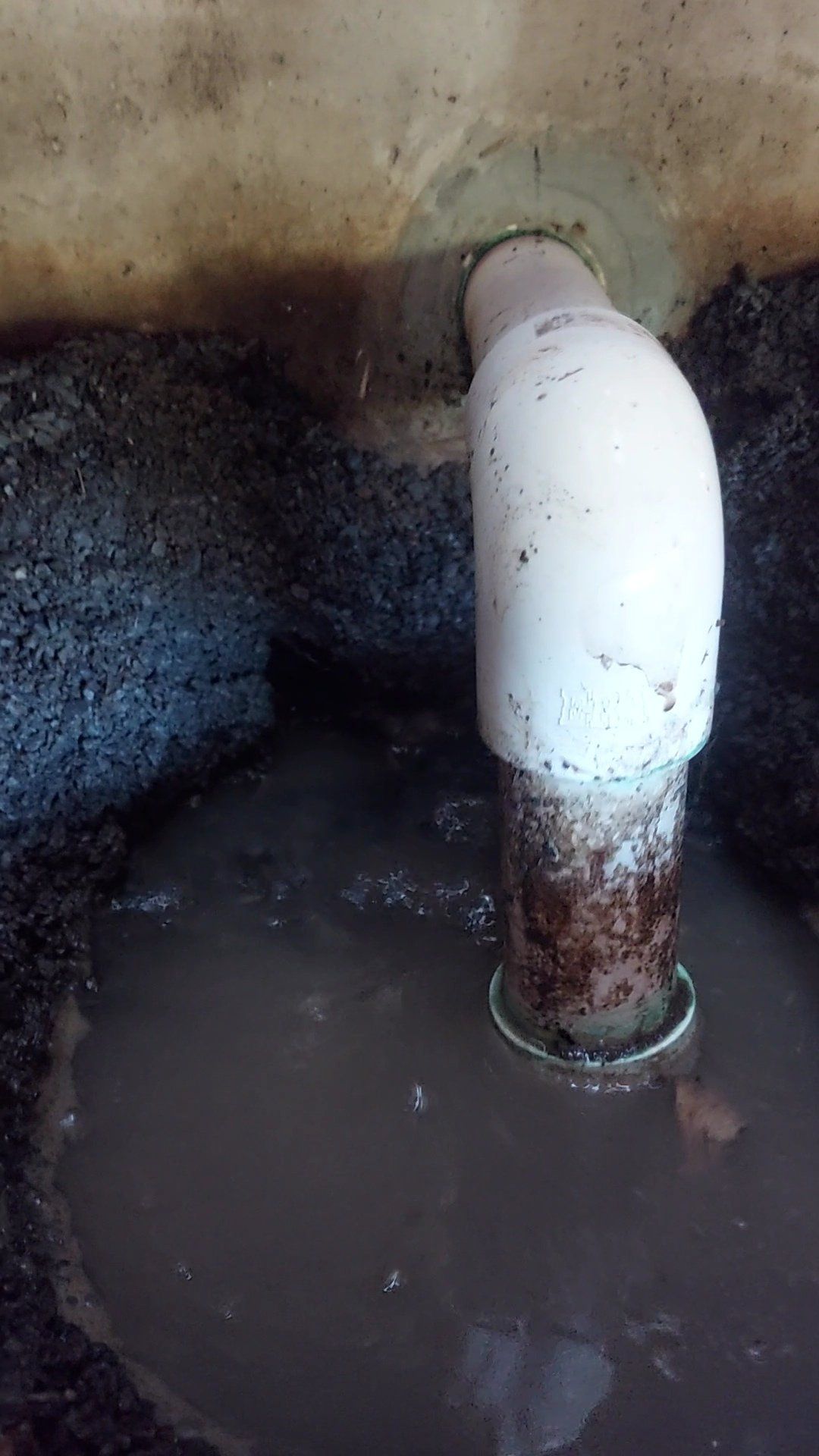 A white pipe is coming out of a hole in the ground.