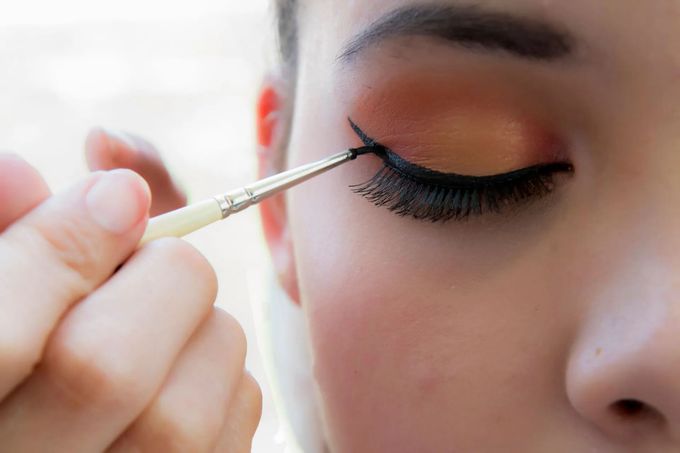 Primo piano di un pennello che applica l'eyeliner nero sulla palpebra superiore di una persona.