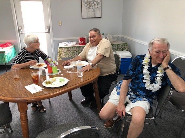 A group of people are sitting around a table with plates of food