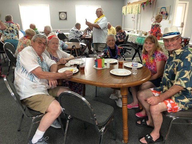 A group of people are sitting around a table with plates of food