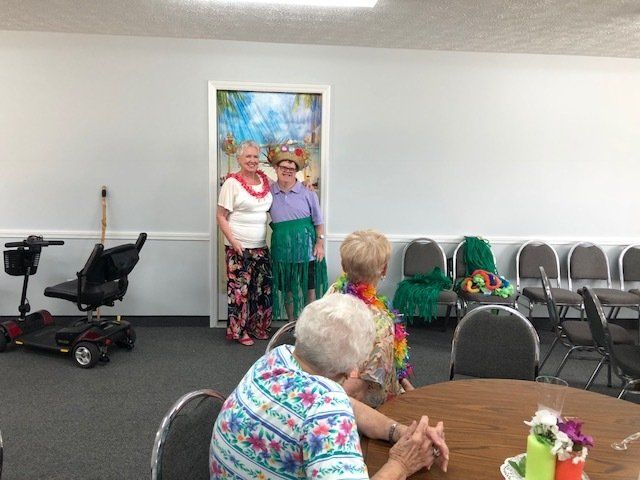 A group of elderly women are sitting at a table in a room.