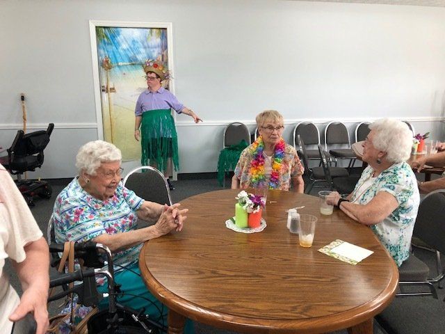 A group of elderly women are sitting around a table in a room.