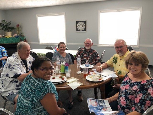 A group of people are sitting around a table with plates of food.
