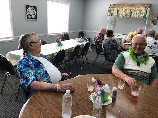 A group of men are sitting at tables in a room.