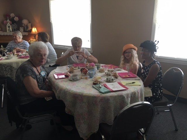A group of people are sitting around a table drinking tea