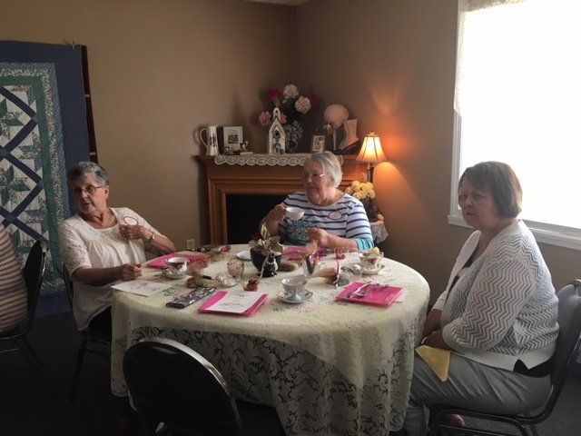 A group of women are sitting around a table drinking tea