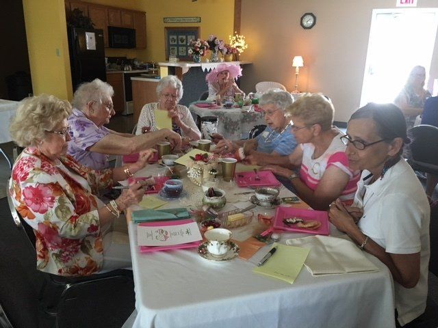 A group of elderly women are sitting around a table