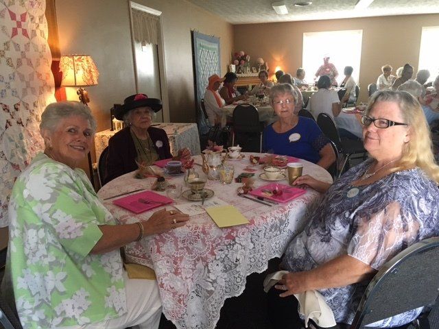 A group of women are sitting at a table with tea cups on it