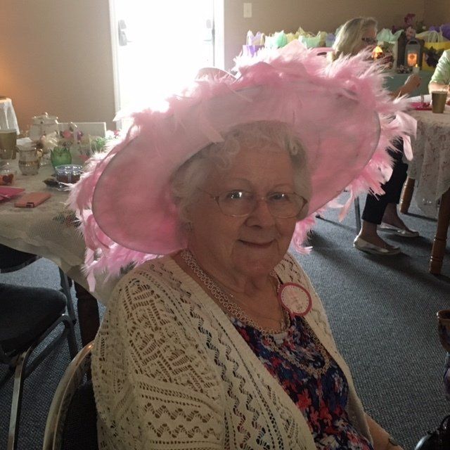An elderly woman wearing a pink hat and glasses