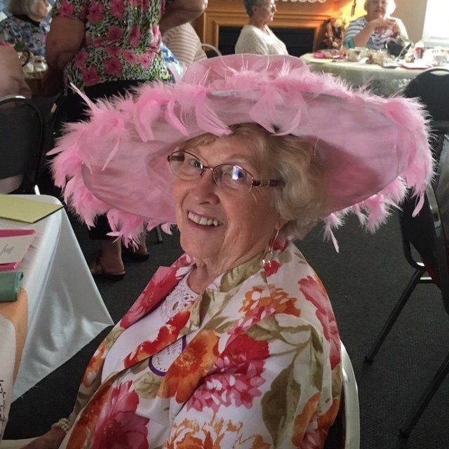 A woman wearing a pink hat and glasses is smiling
