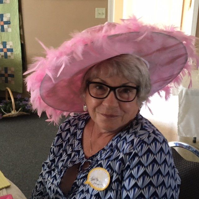 A woman wearing glasses and a large pink hat