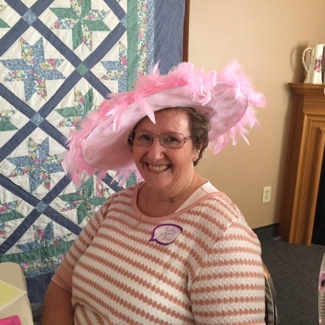 A woman wearing a pink hat and glasses is smiling