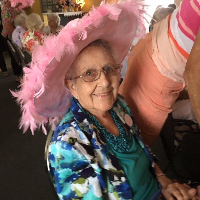 An elderly woman wearing a pink hat and glasses