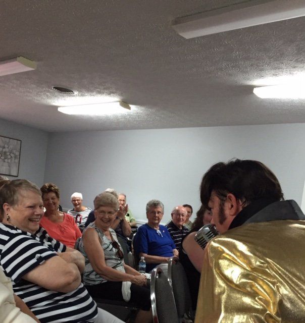 A man in a gold jacket is talking to a group of people