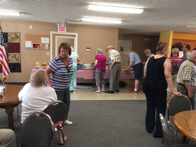 A group of people are gathered in a room with an exit sign