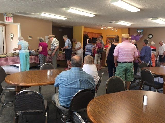 A group of people standing around tables in a room with an exit sign