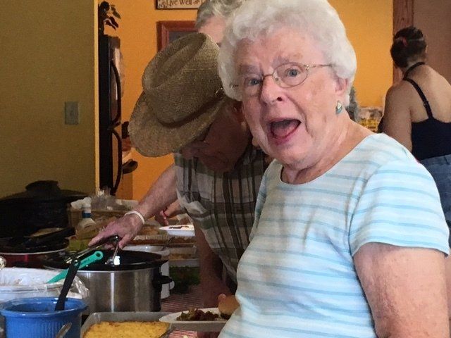 An elderly woman in a blue striped shirt with her mouth open