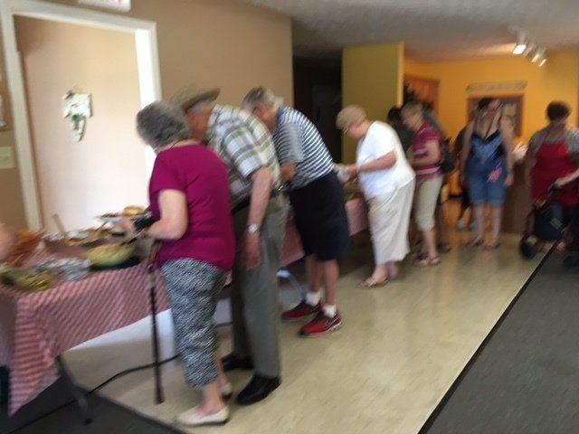 A group of people standing around a table looking at food