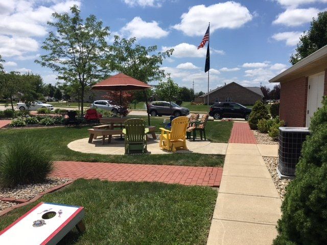 A lawn with a table and chairs and a cornhole board