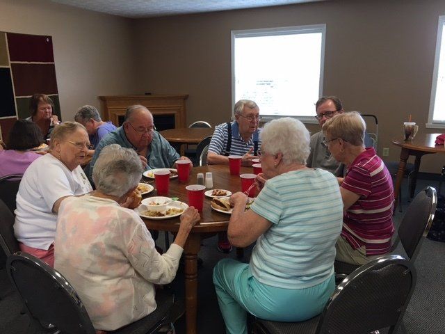 A group of people are sitting around a table eating food.