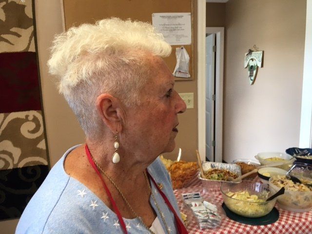 A woman with a shaved head sits at a table with food