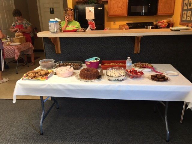 A table with a white table cloth and a variety of desserts on it