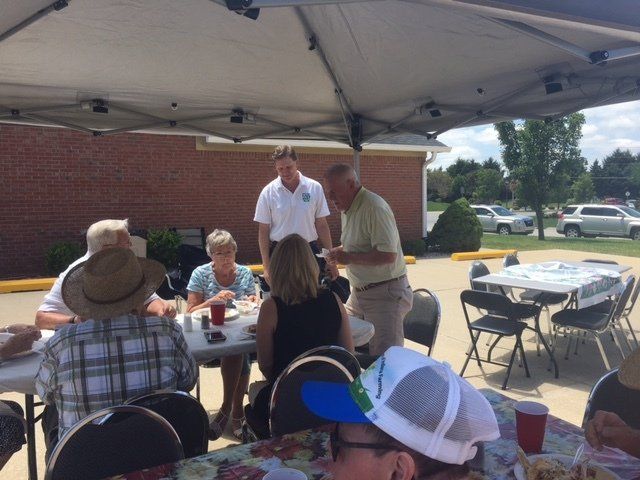A group of people sitting at tables under an umbrella
