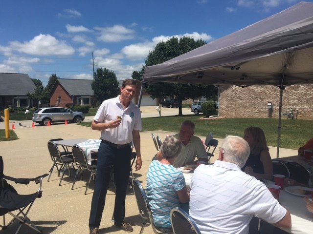 A man is talking to a group of people under a tent