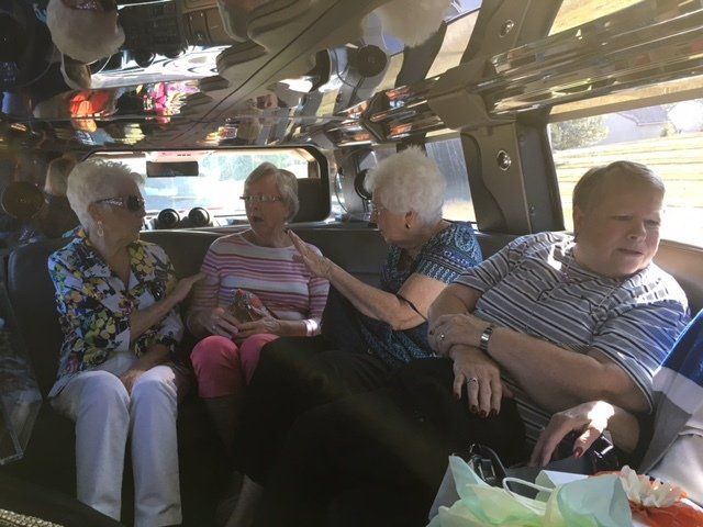 A group of people are sitting in the back of a van talking to each other.