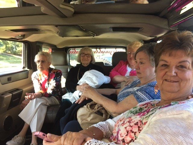 A group of older women are sitting in the back of a car.