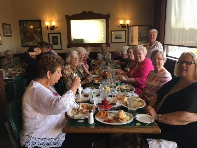 A group of people are sitting at a long table eating food.