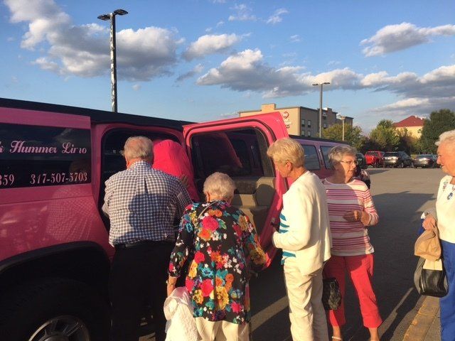 A group of people are getting out of a pink limousine