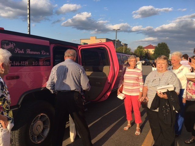A group of people standing in front of a pink limousine
