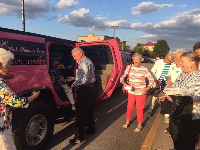 A group of people standing in front of a pink limousine