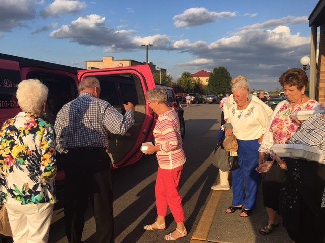 A group of people standing in front of a pink van