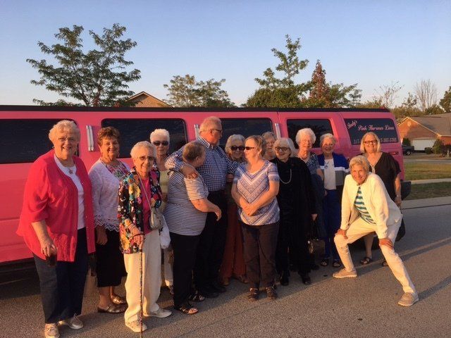 A group of people standing in front of a pink limo