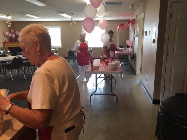 A woman is preparing food in a room with balloons hanging from the ceiling