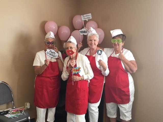 A group of women wearing red aprons and white hats are posing for a picture.