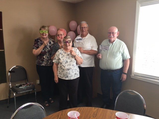 A group of people are posing for a picture in a room with balloons on the wall.