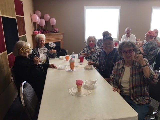 A group of people are sitting at a table eating ice cream