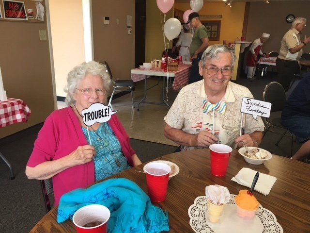 A man and a woman are sitting at a table with a sign that says trouble on it.