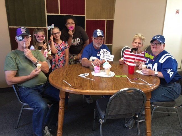 A group of people are sitting around a table eating ice cream