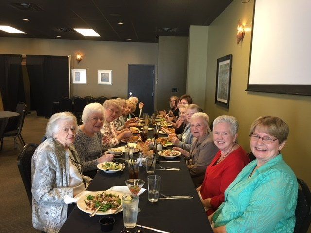 A group of people are sitting at a long table eating food