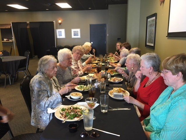 A group of people are sitting at a long table eating food