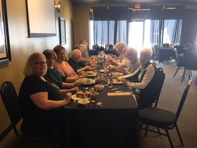A group of people are sitting at a long table eating food