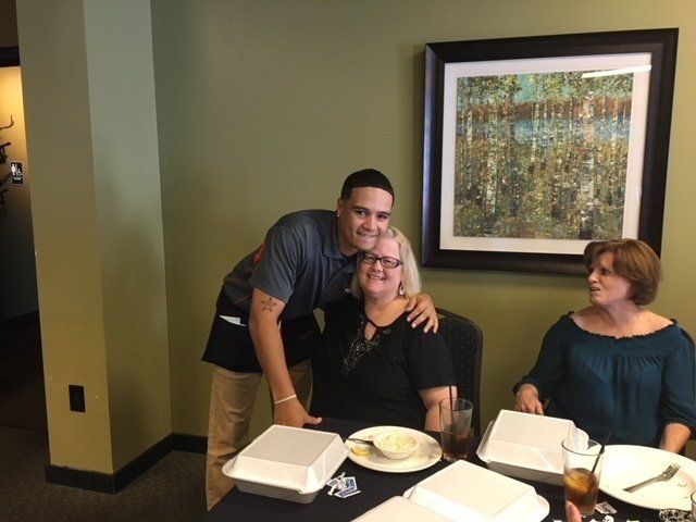 A man and two women are posing for a picture while sitting at a table.